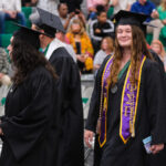 Student smiling and walking the aisle