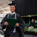 Student smiling while holding their degree