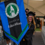 A graduating student carries a banner at commencement