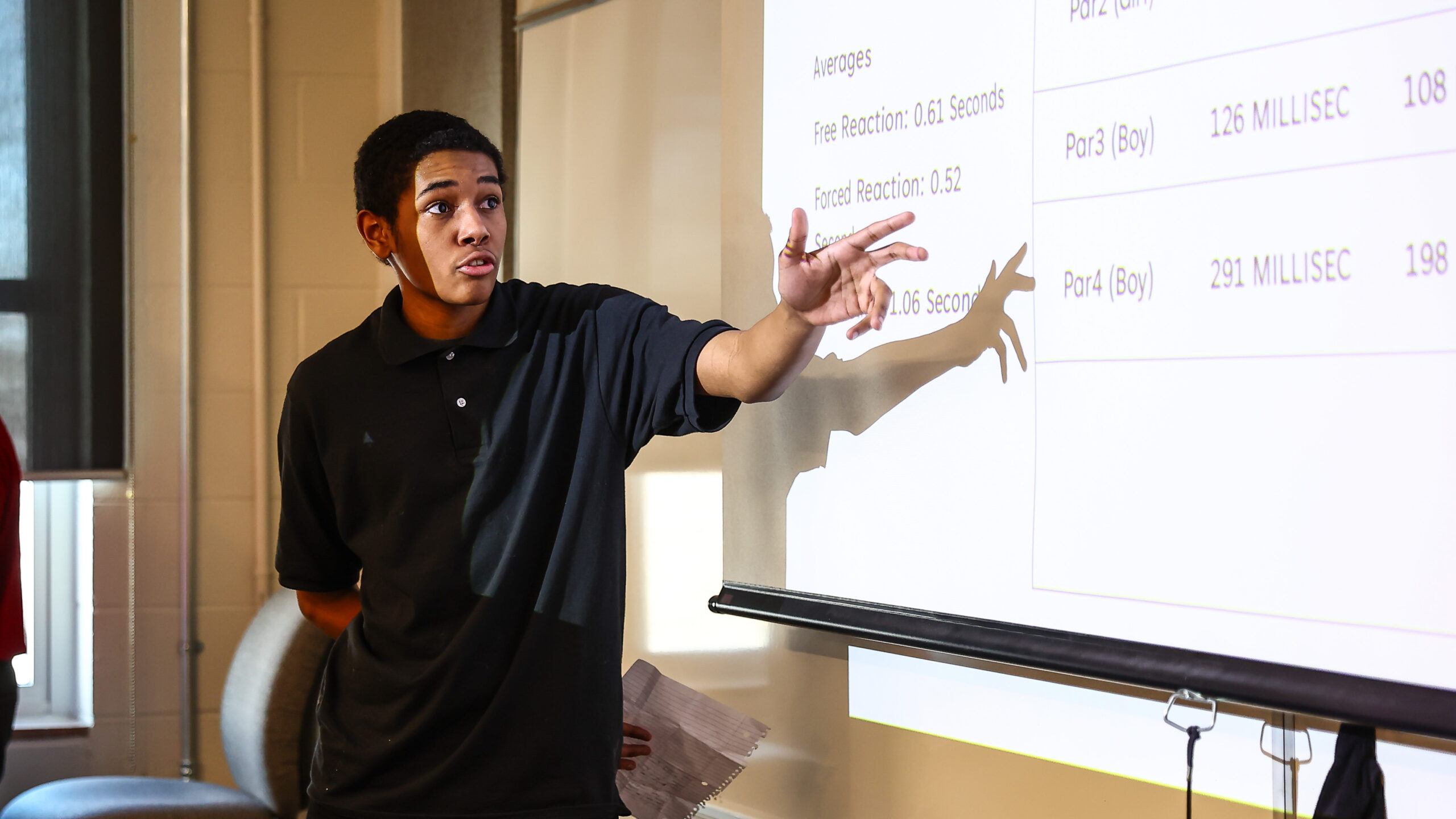 Male high school student presenting in front of a power point