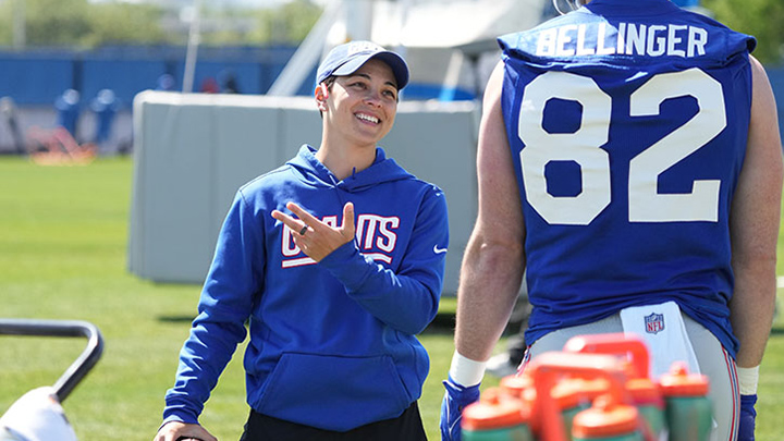 Angela Baker coaches a football player on the field