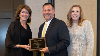 President Riley is handed an awards plaque from two presenters.