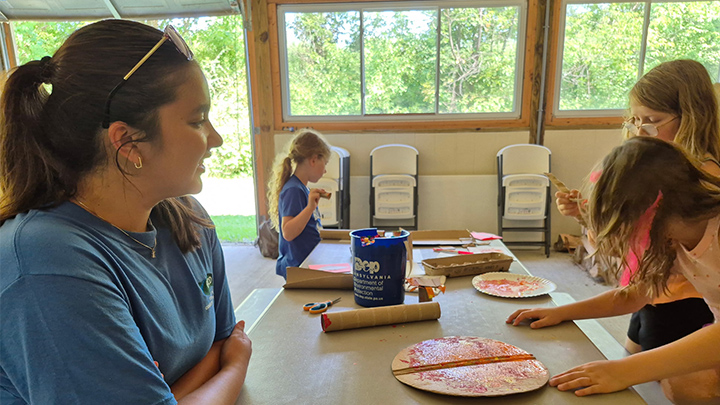 Abigail Nguyen instructs children on how to paint with natural ingredients at the Headwaters Park Nature Center in Erie during the Eco Art in the Park event on July 29.