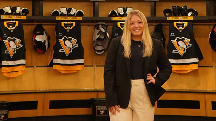 Bailey Kuhn standing in the front of Pittsburgh Penguins jerseys.