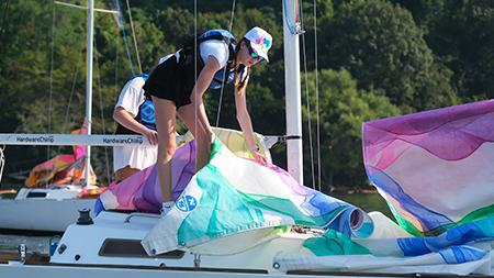 An SRU student unfurling a sail cloth aboard a boat.