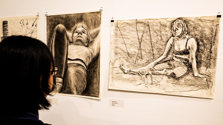 Student observing artwork in the "Drawing: Endlessly Fascinating, Not an End Result" exhibition.