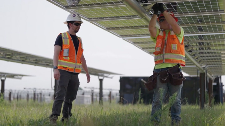Nathan Thompson on a solar farm speaking to a worker.