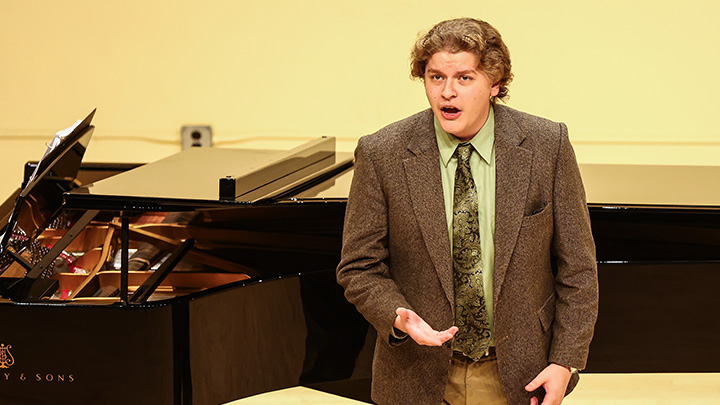 Man singing in front of a piano.