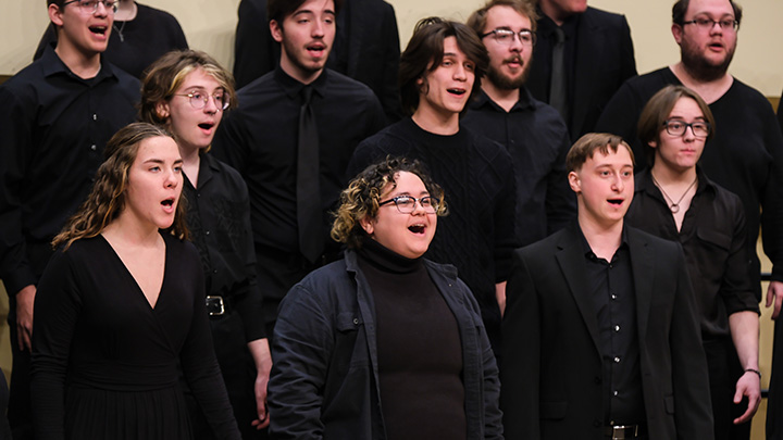 Group of choir singers dressed in black performing.