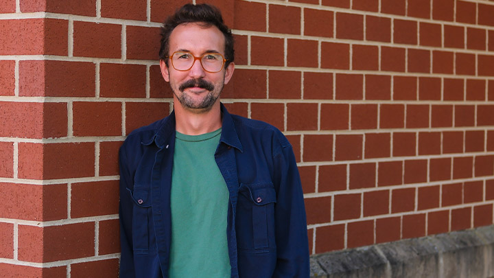 Patrick McGinty standing by a brick wall.