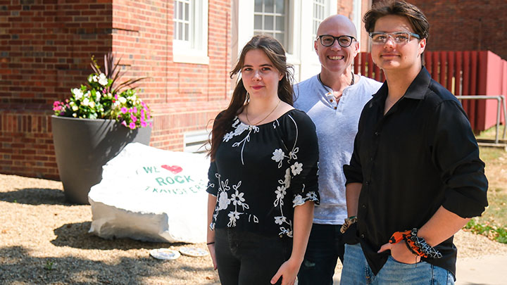 From left, Calliope, Jason and Sabastien Rabold add their signatures to the “We Love Rock Transfers” rock outside of North Hall that celebrates SRU transfer students.