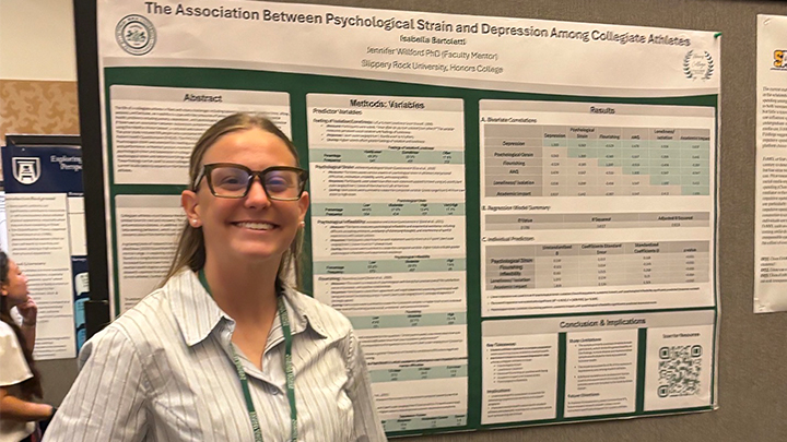 Student standing in front of a research poster at a conference.