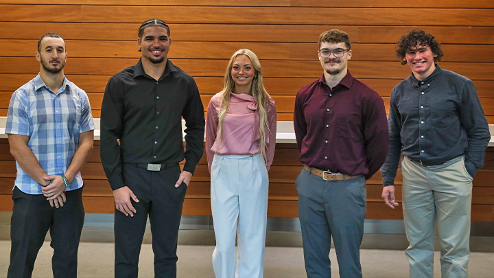Five students standing in business casual attire.