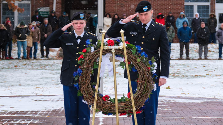 ROTC cadets saluting a wreath in honor of the fallen.