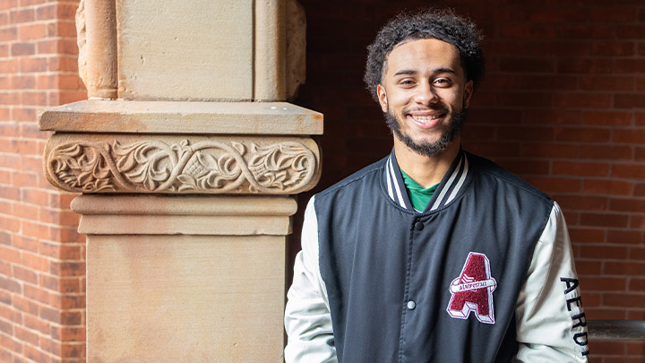 Student standing in front of a pillar.
