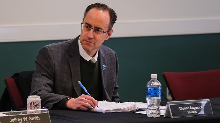 SRU trustee Alfonso Angelucci sitting at a table holding a pen.