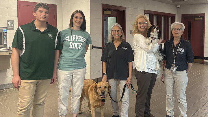 From left, Ben Porter and Neva Lilla stand inside the Crawford County Correctional Facility with Debbi Martell and her lab Titus; Yvonne Eaton-Sull holding Tucker the cavalier and Tucker’s handler, Ardis Walsh.
