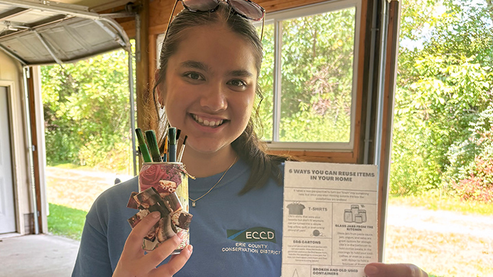 Abigail Nguyen holds a craft and paintbrushes and a pamphlet.