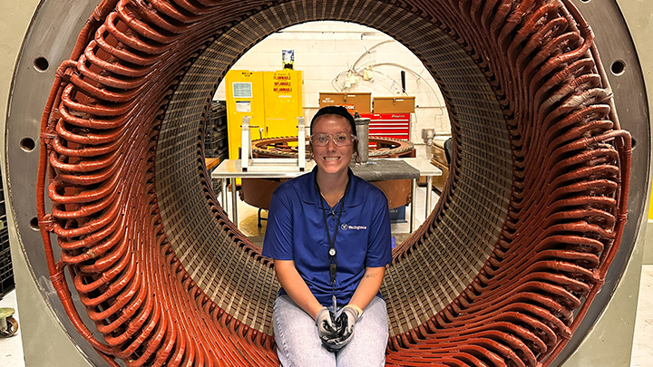 Brianna Forrest, an SRU senior corporate security and homeland security major, sits in the stator of a generator at Westinghouse Electrical plant during her summer internship.