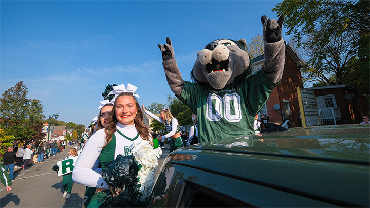 Cheerleader and the Rocky mascot in a truck on parade route.