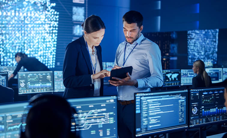 Cybersecurity stock image with two people looking at a tablet in a computer lab.