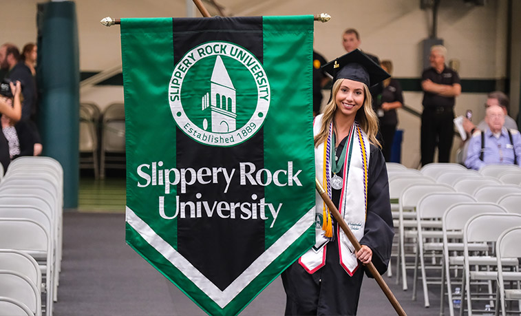 A graduating student carries an SRU flag at commencement