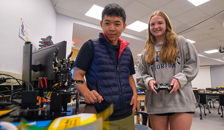 From left, Slippery Rock University professor Jheng-Wun Su and SRU student Janey Parks work in the Advanced Manufacturing Lab operating a robotic hand that will be used to test wearable sensors that capture human movements.