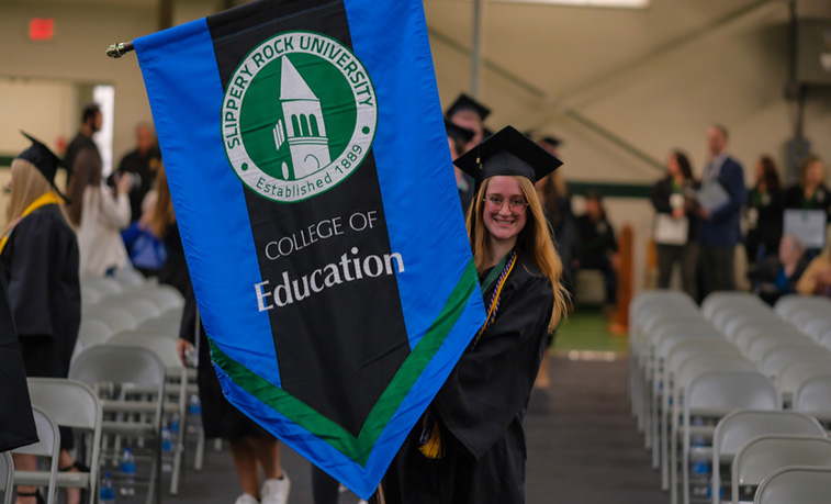 A graduating student carries a banner at commencement