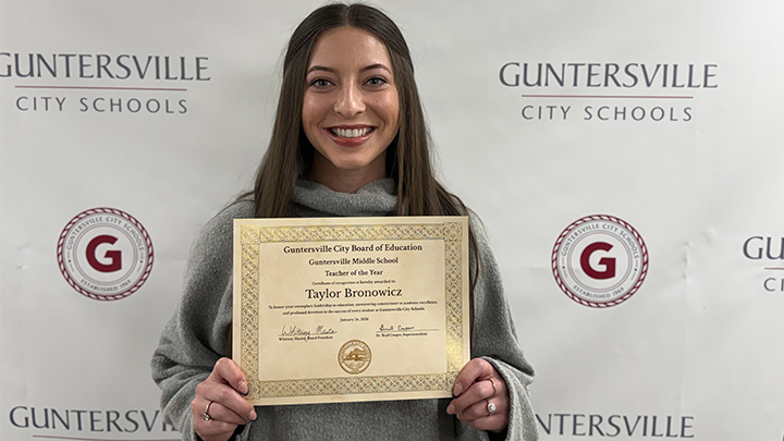 Teacher holding an awards certificate.