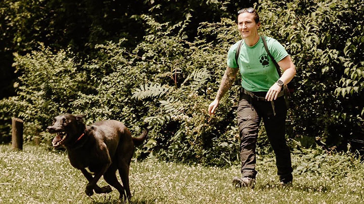 Running dog followed by woman.