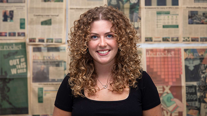 Chloe's portrait in the newsroom with newspapers on the wall.