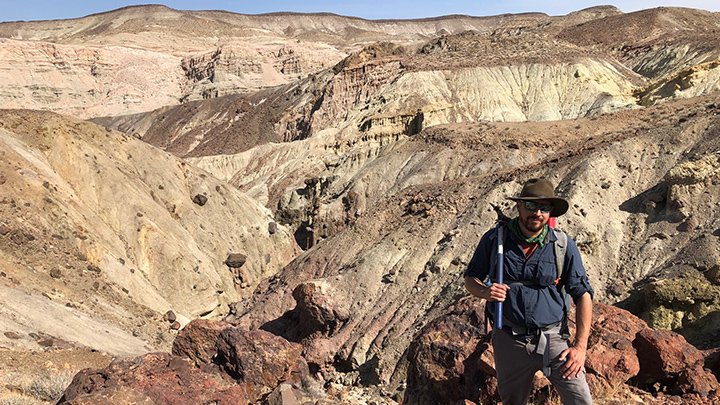 Man with pick ax standing near an excavation site