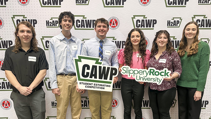 Six students standing in a line holding two signs that say CAWP and Slippery Rock University.