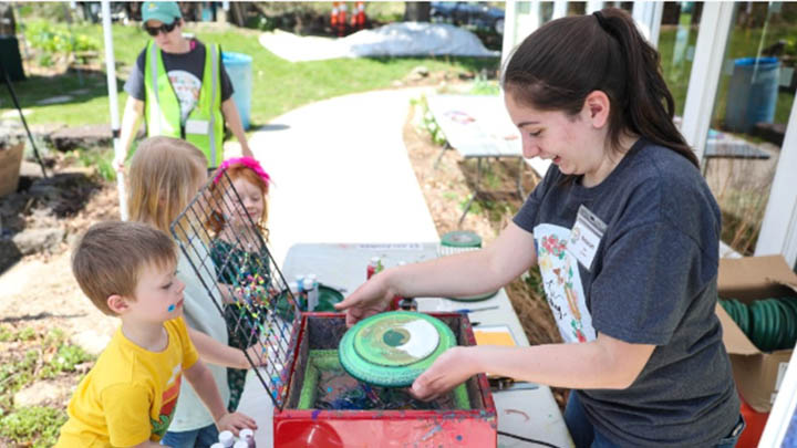 Women conducting painting demonstration with three children