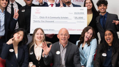Giant check with people waving and celebrating around it.
