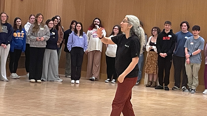 Woman walking and presenting with students standing in background.