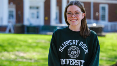 Woman in SRU sweatshirt standing in campus quad.