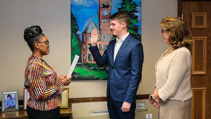From left, Shannon Young, administrative assistant in human resources and notary public of the University, reads an oath of office to SRU student Alex Momyer, alongside SRU President Karen Riley, as Momyer is sworn in as a member of the SRU council of trustees on April 28 in Riley's office at Old Main.