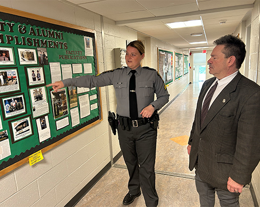 From left, Cpl. Nicole Ludwig talks with SRU professor David Champion as they recognize graduates celebrated on a bulletin board from SRU’s criminology and criminal justice program who have gone on to successful careers.