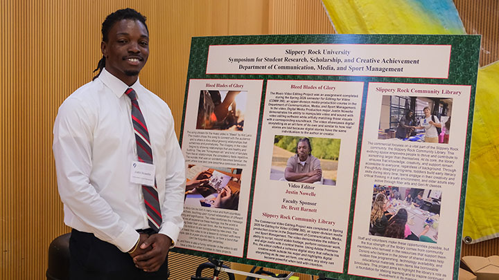 Student standing next to a poster.