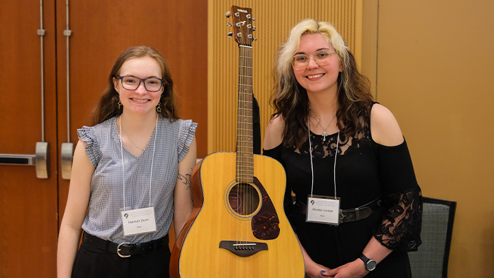 Two women with a guitar between them.