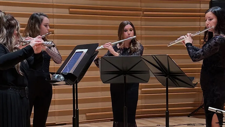 Four flutists playing their flutes.