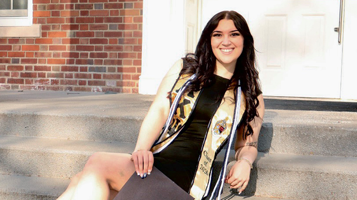 Women sitting on steps with graduation gown and stole.