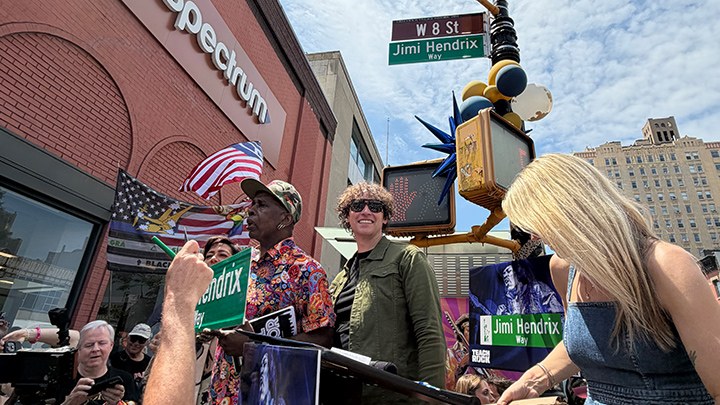 Two men standing by a street sign that says Jimi Hendrix Way.