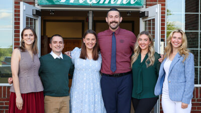 Group photo of six people standing at a doorway entrance.