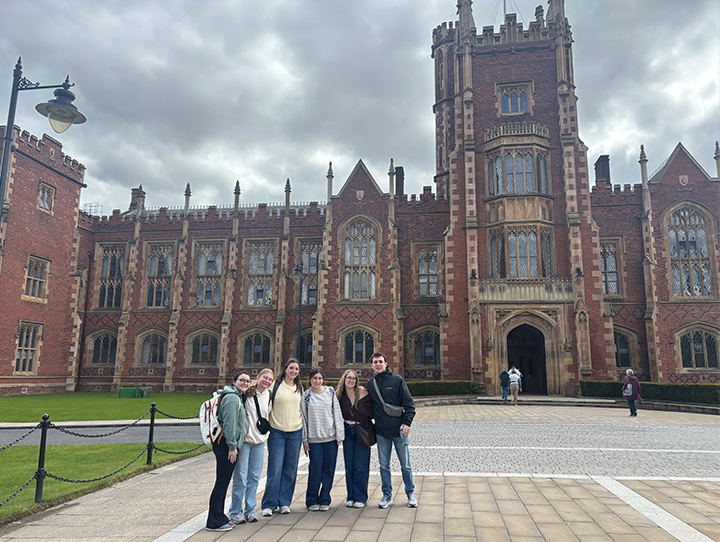 Six students standing outside a cathedral entrance.