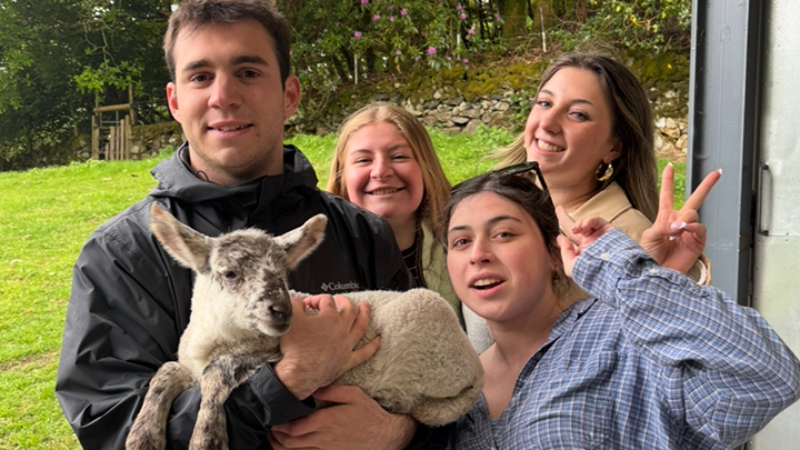 Four students with one holding a sheep.