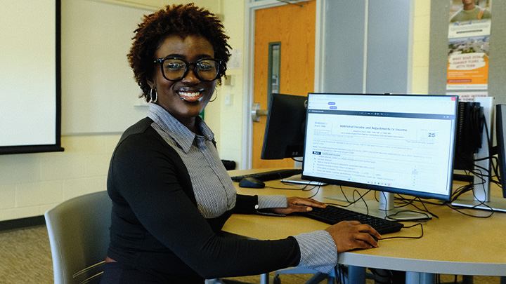 Women smiling and sitting at a computer.