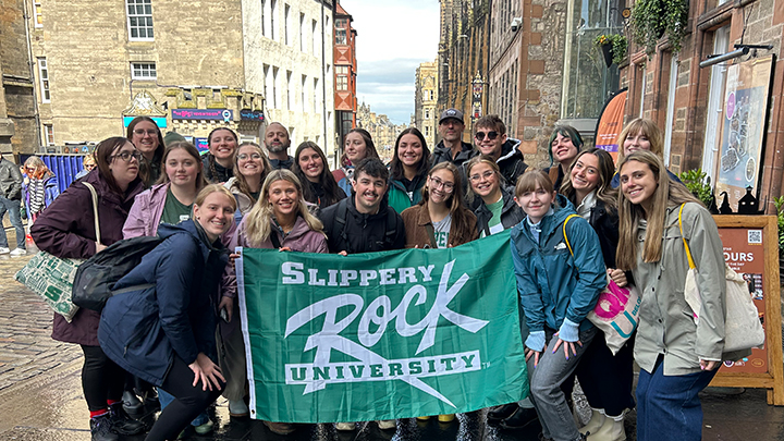 Group of 20 people standing in city street holding SRU flag.