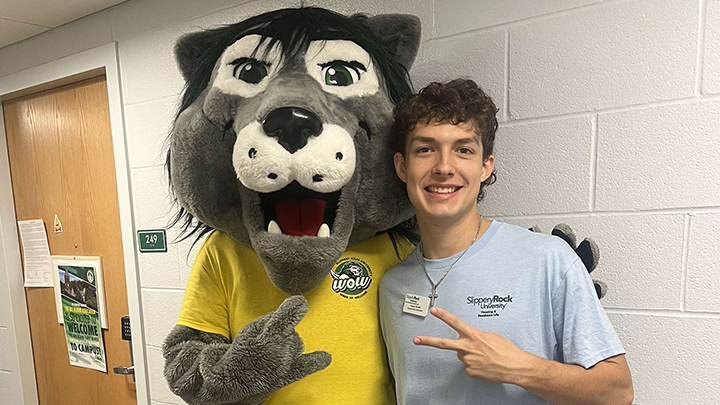 Rocky mascot posing with Owen Durka outside of a dorm room.